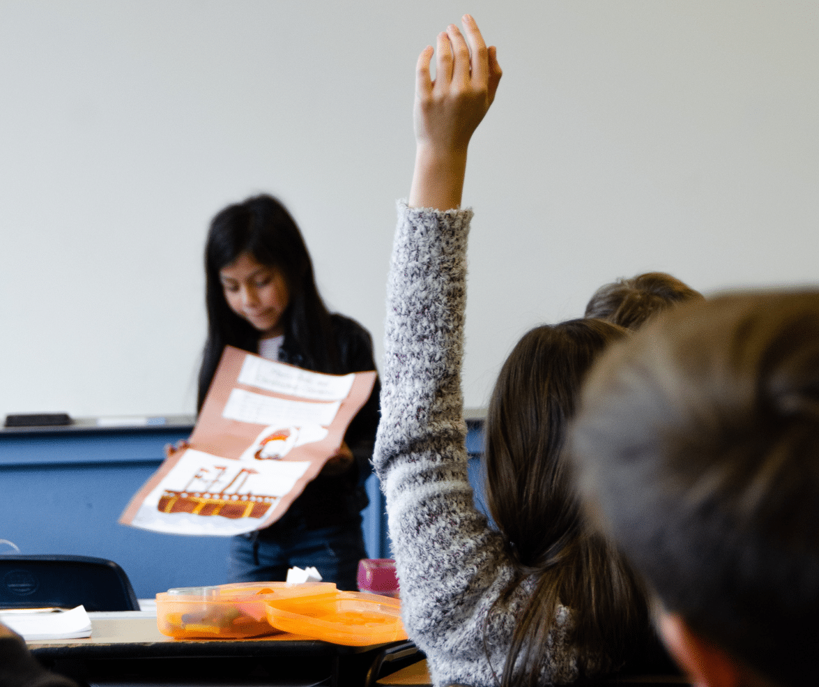 Girl raises hand in classroom.